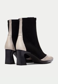 Svart mocka och silverläder ankelstövlar med hög klack och rund tå. Har en delad design med kontrasterande texturer.
