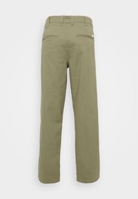 Olivgrüne, gerade geschnittene Hosen aus Baumwolle. Mit zwei Gesäßtaschen mit Reißverschlüssen und einem Taillenbund mit Gürtelschlaufen.