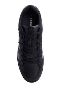 Zapatilla deportiva negra con parte superior de cuero suave, paneles laterales texturizados, cordones redondos y cuello acolchado. Talla 39 indicada en el interior.