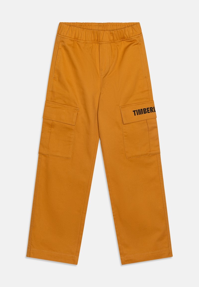 Pantalon cargo jaune moutarde avec taille élastique, poches à rabat sur les côtés et logo partiel « Timberland » sur le rabat de la poche droite.