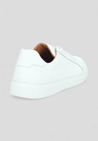 Białe skórzane sneakersy o gładkiej fakturze, zaokrąglonym kształcie, niskoprofilowej podeszwie i minimalistycznym designie. Posiadają przeszywane akcenty oraz beżowe wnętrze.