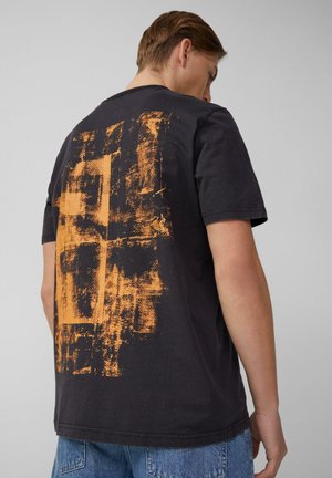 Zwarte katoenen t-shirt met een abstract oranje grafisch ontwerp op de rug. Korte mouwen en een normale pasvorm met een ronde hals.