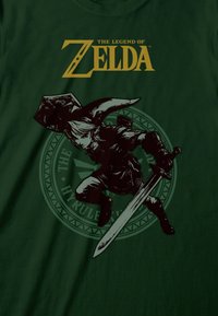 Dunkelgrünes T-Shirt mit Link aus "The Legend of Zelda" in Schwarz, mit Schwert, Schild und dem Hyrule-Symbol im Hintergrund.