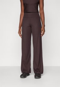 Ribmede brune brede bukser med elastisk talje, parret med en matchende cropped top. Stoffet ser blødt og strækbart ud.