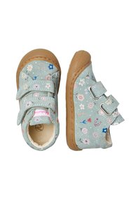 Dětské boty s hnědými gumovými podrážkami a květinovým vzorem na světle zeleném textilu, upevněné pomocí dvou suchých zipů.