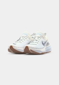 Nike running shoes with a white knit upper, light blue accents, and a brown rubber outsole. Features padded collar and embossed logo.