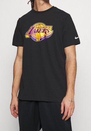 Osoba nosząca czarną koszulkę z dużym logo Los Angeles Lakers i białym znakiem Nike na rękawie.