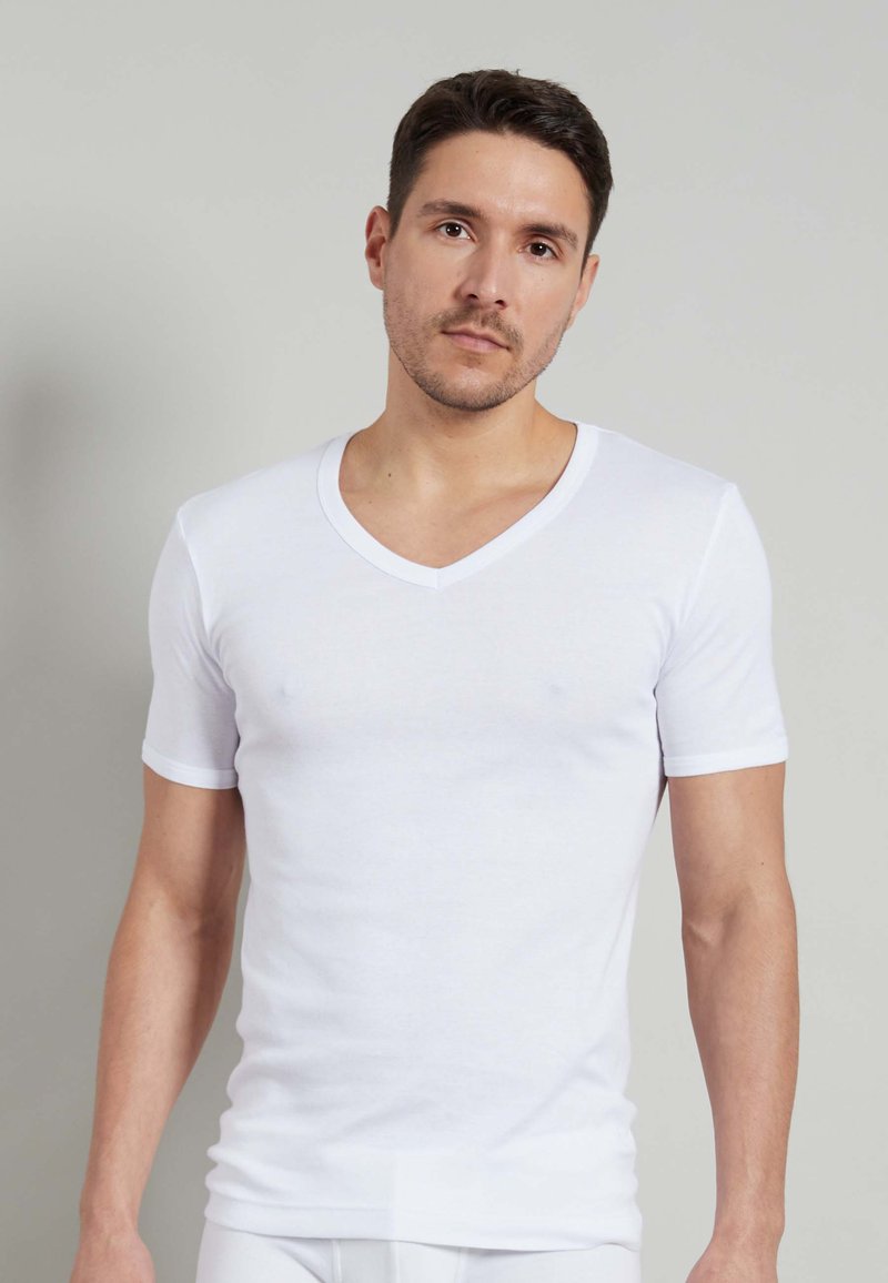 T-shirt bianco a maniche corte e scollo a V realizzato in un morbido misto cotone, con una silhouette aderente e cuciture minime.