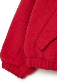 Chaqueta de forro polar rojo con puños de canalé y un bolsillo con tapa. Textura suave y color sólido, que destaca su calidez y diseño informal.