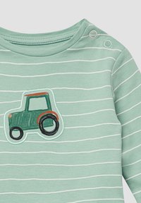 Groene gestreepte langemouwen shirt met een tractorapplicatie in groen, oranje en zwart. Voorzien van drukknopen op de schouder.