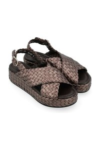 Sandali in bronzo intrecciato con suola a piattaforma, cinturini incrociati, punta aperta e cinturino alla caviglia regolabile. Finitura texturizzata.