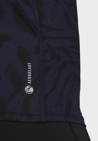 Top atlético azul marino hecho de material transpirable con un patrón texturizado, que presenta un logo visible y detalles de costura en contraste.