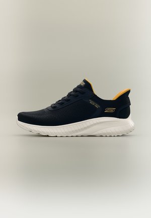 Baskets Skechers Slip-Ins noires et jaunes avec semelle blanche, design respirant et logo sur le côté et la languette, vues de profil.