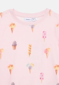 Sudadera de color rosa claro con un patrón colorido de conos de helado y paletas. Material de algodón suave con cuello redondo y ribetes acanalados.