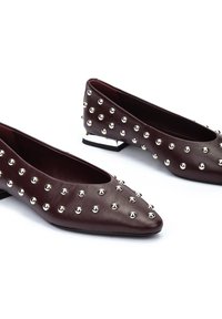Scarpe flat bordeaux in pelle liscia, con borchie argento disposte sulla superficie, punta accentuata e tacco basso.