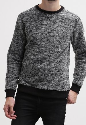 Sudadera negra y gris con patrón, cuello redondo, puños y dobladillo acanalados, con un pequeño detalle de logo. Textura de tela suave.