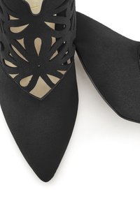 Zapatos negros de punta con diseño floral recortado y superficie texturada. Presentan una plantilla de color beige y una sección del tacón suave.