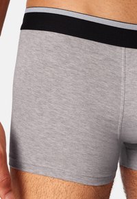Boxer shorts in cotone grigio con un elastico in vita nero e grigio, caratterizzati da una superficie liscia e un design aderente.