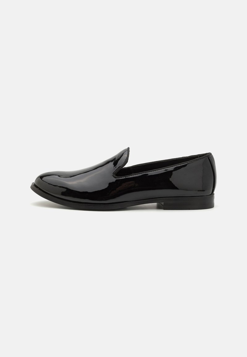 Melna patentēta ādas slip-on kurpe ar nedaudz norādītu purngalu, gludu tekstūru, minimālu šuvju daudzumu un zemu papēdi.