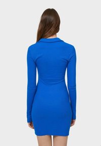 Robe bleue à manches longues avec une silhouette ajustée, une texture côtelée et un col. Le design est simple, sans motifs ni ornements visibles.