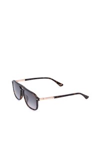 Lunettes de soleil écaille avec verres carrés à dégradé foncé et fins accents dorés sur les branches, inclinées sur fond blanc.