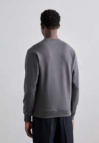 Gray sweatshirt with a crew neckline, long sleeves, and ribbed cuffs. Smooth texture, relaxed fit, and no visible patterns or logos.