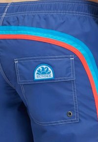 Boxer da bagno blu con una tasca posteriore caratterizzata da un logo blu circolare, impreziosito da strisce azzurre, arancioni e blu scuro.