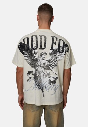 T-shirt en coton couleur crème avec un grand motif noir représentant un ange et un chien au dos, avec le texte "GOOD FOR NOTHING."