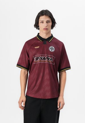 Maroon polo shirt made of lightweight fabric with a textured pattern, featuring a black collar and cuffs with yellow accents and logo.