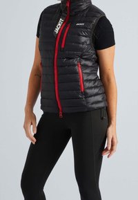 Gepolsterte schwarze Weste mit roten Reißverschlüssen, hohem Kragen und Markenetikett. Verfügt über zwei vordere Reißverschlusstaschen und hat eine taillierte Passform.