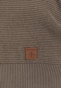 Brauner Strickpullover mit strukturiertem Muster und geripptem Saum. Enthält ein rechteckiges Lederetikett mit dem eingeprägten Schriftzug "KEY LARGO."
