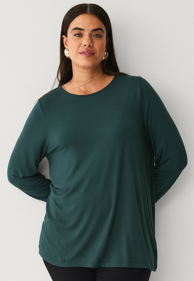 Dark green long-sleeve t-shirt made of smooth, lightweight fabric. Round neckline and relaxed fit, with subtle draping at the sides.