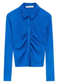 Chemise bleue à manches longues avec un col, en tissu texturé et fronces centrales, fermée par des boutons sur le devant.