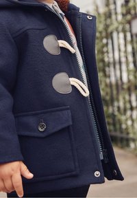 Navyblauer Kapuzen-Dufflecoat mit Reißverschluss, Druckknopf-Verschlüssen und einer vorderen Tasche mit einem Knopf. Weiche Textur mit grauen Akzenten.