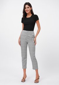 Svart ribbad t-shirt med kort ärm i kombination med grå rutiga högmidjade byxor. Slim-fit, kort modell, lämplig för olika tillfällen.