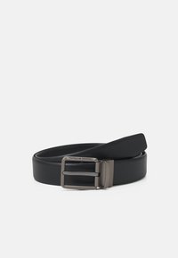 Ceinture synthétique noire au fini texturé, dotée d'une boucle en métal matte portant l'inscription "Porsche Design." Longueur ajustable avec un bord lisse.
