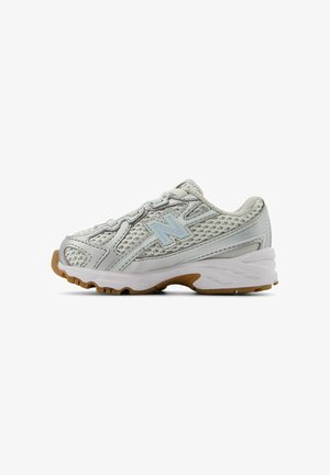 Silver athletic shoe with mesh upper, padded collar, and light blue accents. Rubber outsole features multi-directional treads for traction.