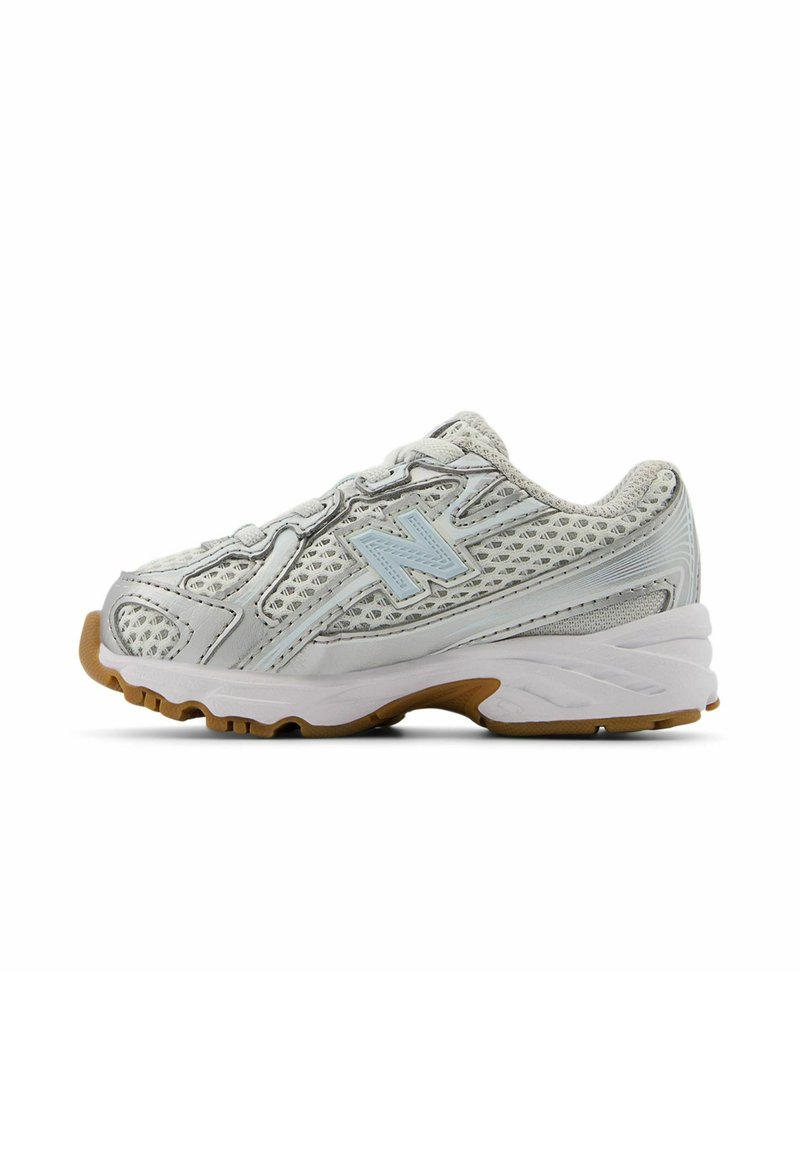 Silver athletic shoe with mesh upper, padded collar, and light blue accents. Rubber outsole features multi-directional treads for traction.