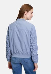 Hellblaue Bomberjacke mit gerafften Ärmeln, elastischen Bündchen und Saum, aus einem glatten Stoff mit lässigem Design.