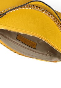 Borsa a tracolla in pelle gialla con finitura testurizzata, dotata di un accento in catena argentata, chiusura a zip e interno beige con una piccola tasca con zip.