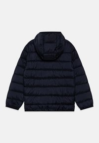 Giacca puffy blu navy con cappuccio, caratterizzata da un design trapuntato, polsini elasticizzati e una finitura liscia e lucida. Nessun marchio visibile.