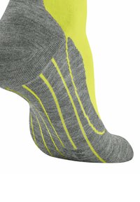 Zbliżenie na szarą skarpetę z żółtymi akcentami. Cechy obejmują teksturowany materiał i linie wzoru wzdłuż boku, skupiając się na komforcie i przyczepności.