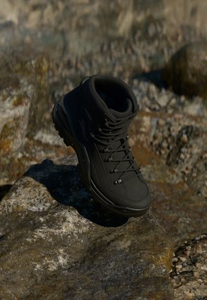 Zwarte wandelschoen met hoge enkelsupport, gestructureerd materiaal, metalen oogjes en veters, met een robuuste zool voor grip.