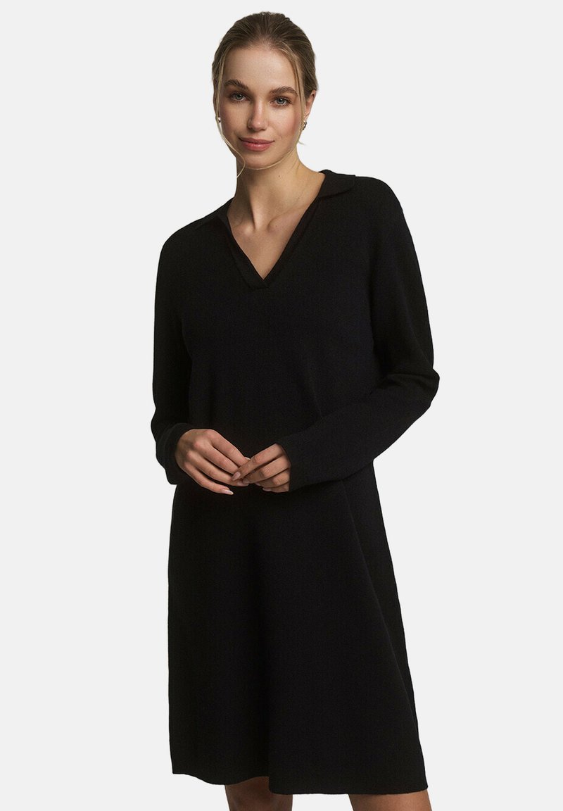Czarna, długa sukienka z długim rękawem, dekoltem w kształcie litery V i kołnierzykiem. Wykonana z miękkiego materiału, o luźnym kroju i długości powyżej kolan.