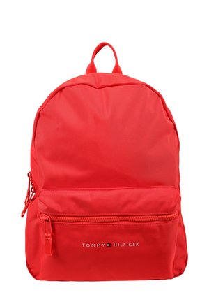 Zaino in nylon rosso con forma arrotondata. Presenta una tasca frontale con zip e una maniglia superiore. Logo "TOMMY HILFIGER" visualizzato in bianco.