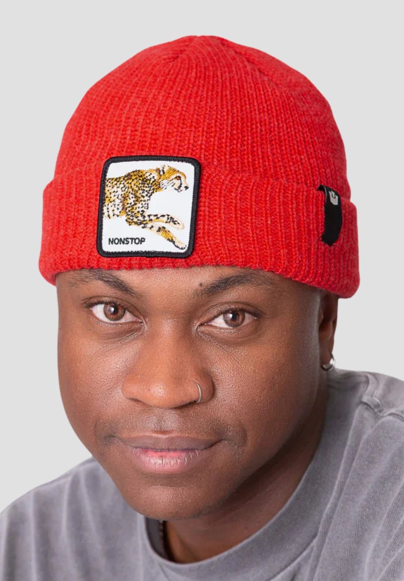 Rote gestrickte Beanie mit umgeschlagenem Saum, ausgestattet mit einem bestickten Leoparden-Patch und dem Text "NONSTOP." Weiche Textur, gerippte Gestaltung.