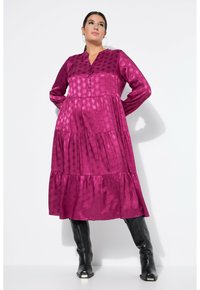 Fuchsia Schichtkleid mit strukturiertem Muster, langen Ärmeln und einer Vorderseite mit Knopfleiste. Kombiniert mit kniehohen schwarzen Stiefeln.
