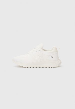 White athletic sneaker with textured sole, lace-up design, breathable mesh sides, and small "cK" logo on the heel counter.