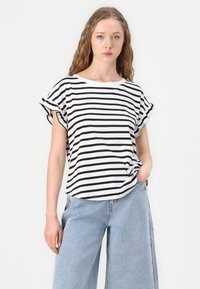 Black and white striped t-shirt with a round neckline, short rolled sleeves, and soft cotton material. Paired with light blue wide-leg jeans.