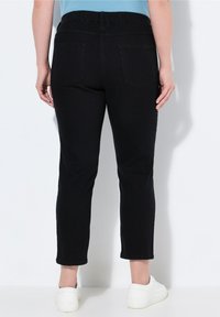 Černé kalhoty z bavlněné směsi s volným střihem, elastickým pasem a dvěma zadními kapsami. Lem sahá těsně nad kotník. Nosit se bílé tenisky.